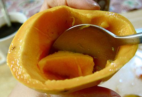 Estrazione di polpa di mango con un cucchiaio