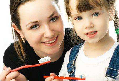 donna con una ragazza con spazzolini da denti in mano