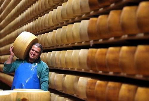 Un uomo in un magazzino porta una testa di formaggio