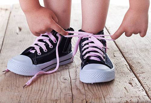 Bambino che lega i lacci delle scarpe da ginnastica