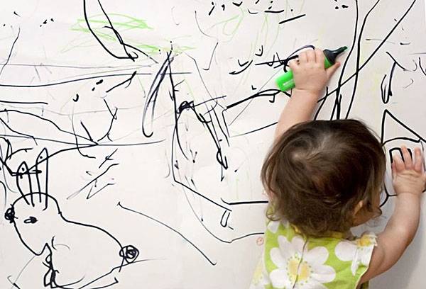 Il bambino disegna su un muro bianco