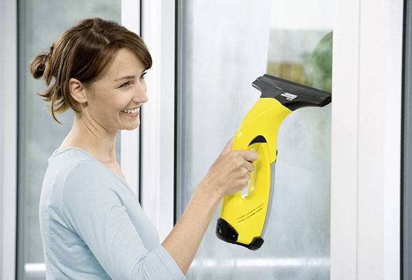 La ragazza pulisce le finestre con il tergicristallo di Karcher