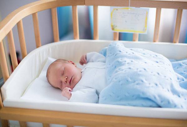 Bambino nella culla sotto le coperte