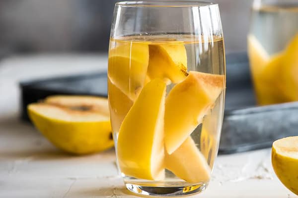 Fette di mela cotogna in un bicchiere con acqua