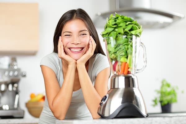 La ragazza fa il frullato di spinaci.