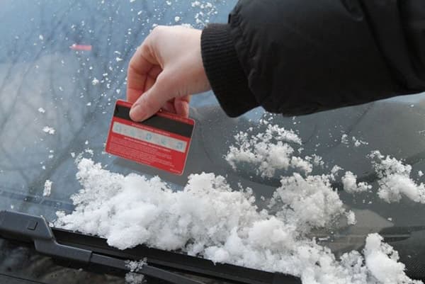 Pulire l'auto dalla neve con una carta di plastica