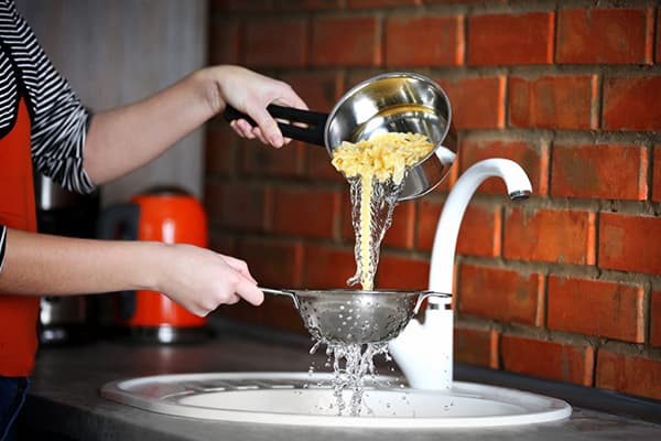 Woman drains water after cooking pasta