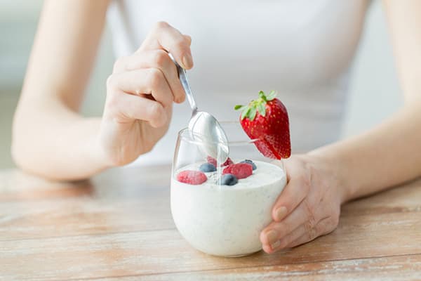 Ragazza che mangia yogurt magro con le bacche