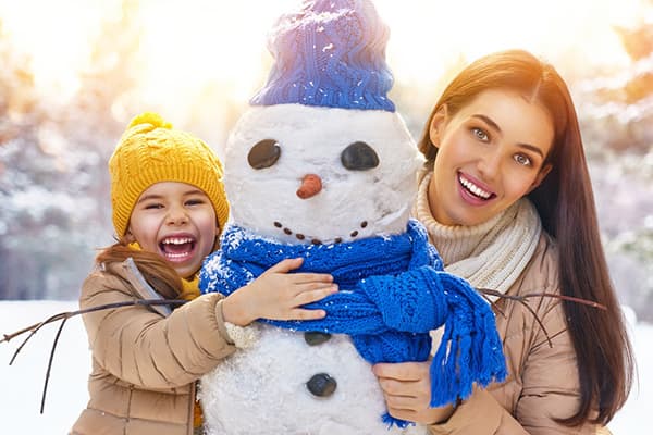 Mamma e figlia stanno scolpendo un pupazzo di neve